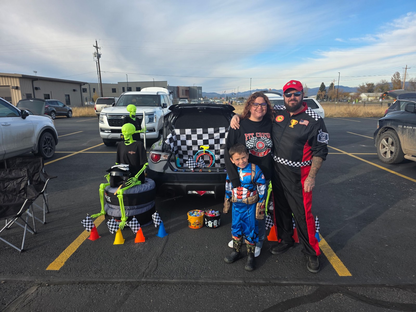 DJ Denton and family at a community trunk-or-treat in Helena, with the Velocity Racing racing-themed display