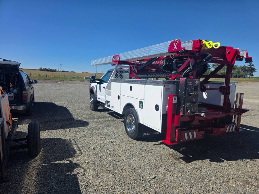 Pump-hoist service truck cleaned on site, with the Velocity Racing wash rig alongside